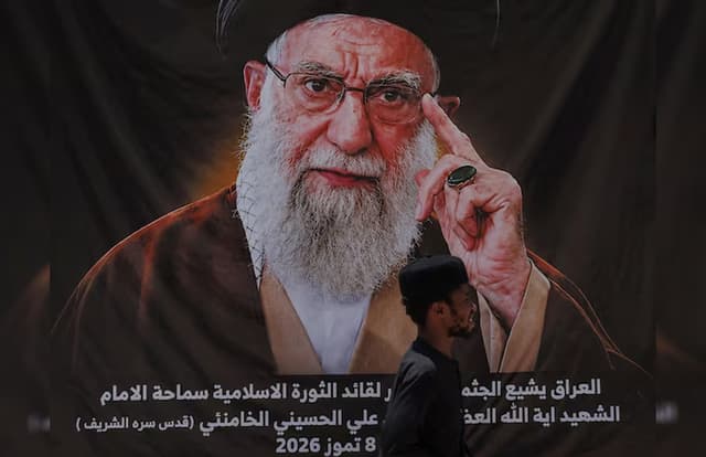 A man walks past a banner bearing a portrait of Iran's late Supreme Leader Ayatollah Ali Khamenei ahead of funeral processions in Najaf.
